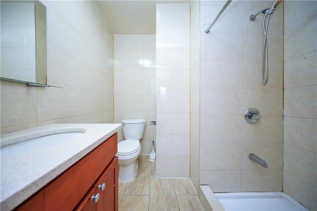 bathroom featuring tile walls, toilet, vanity, and tiled shower