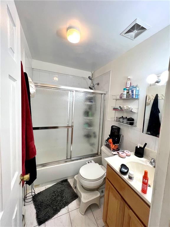 full bathroom featuring shower / bath combination with glass door, backsplash, tile floors, toilet, and vanity