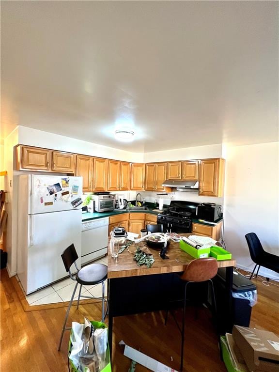 kitchen with sink, light hardwood / wood-style floors, and white appliances