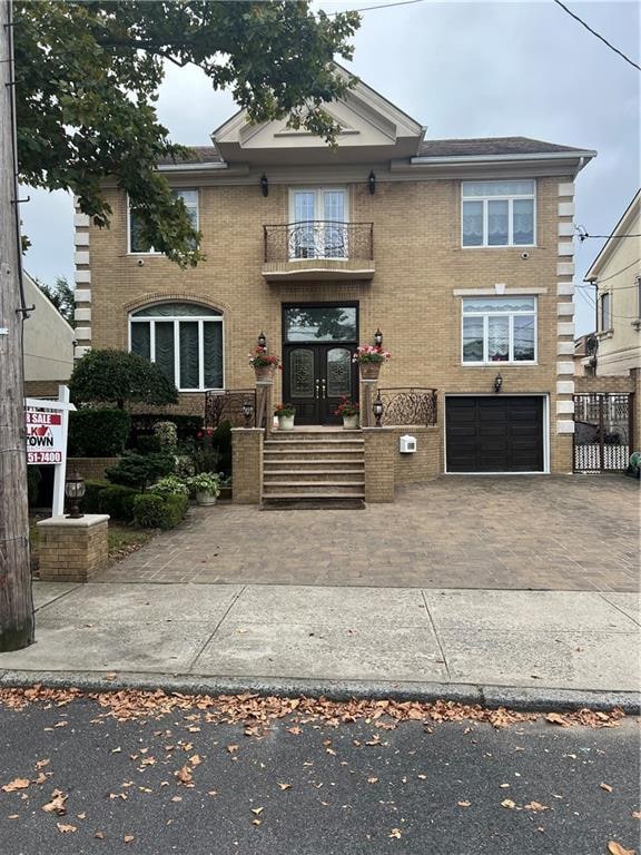 view of front of house featuring a garage, a balcony, and french doors