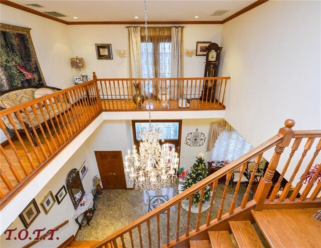 stairway featuring ornamental molding, a towering ceiling, and an inviting chandelier