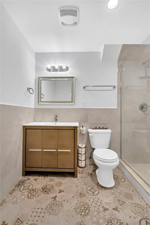 bathroom featuring tile patterned floors, toilet, and tile walls