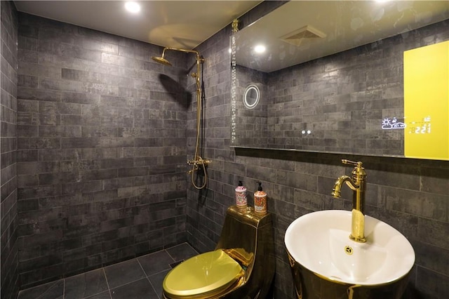 bathroom with visible vents, a tile shower, tile patterned floors, tile walls, and a sink