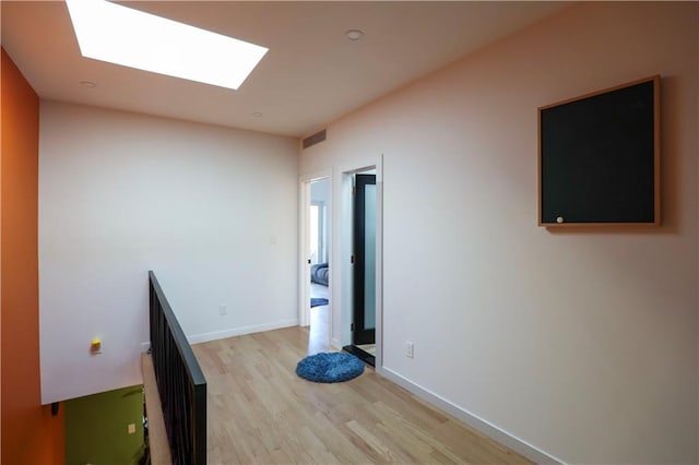 interior space featuring visible vents, a skylight, light wood-type flooring, and baseboards