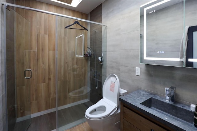 full bath with toilet, tile walls, a stall shower, and vanity