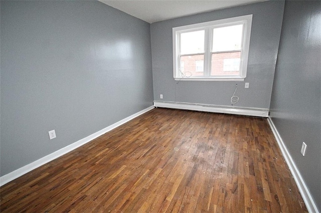 spare room featuring a baseboard radiator and dark hardwood / wood-style flooring