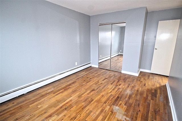 unfurnished bedroom with a baseboard radiator and wood-type flooring