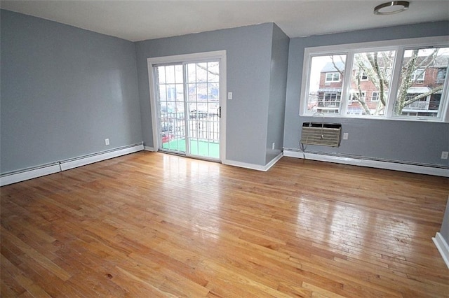 spare room featuring a baseboard radiator, a wall unit AC, and light hardwood / wood-style floors