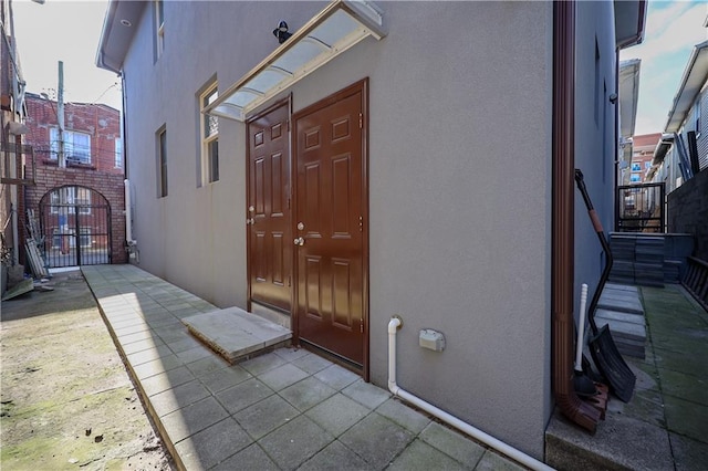 doorway to property featuring a gate and stucco siding