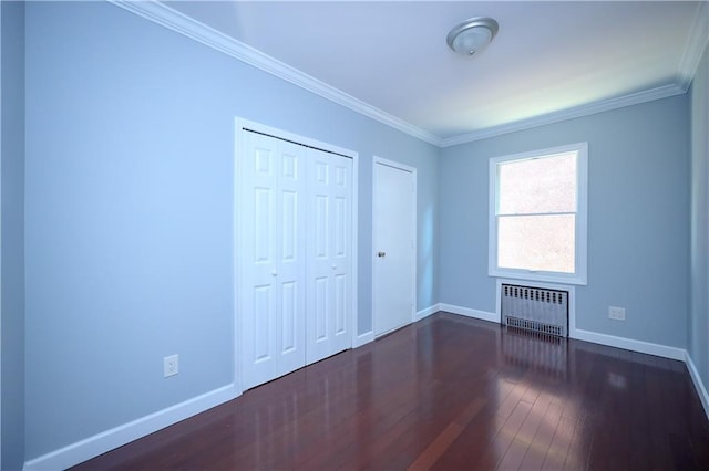 unfurnished bedroom featuring radiator, baseboards, dark wood finished floors, ornamental molding, and a closet