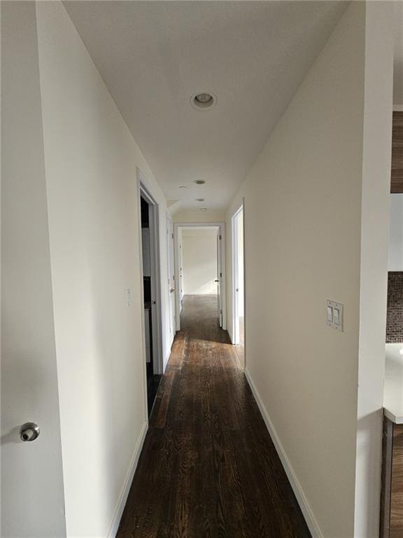 corridor with baseboards and dark wood finished floors