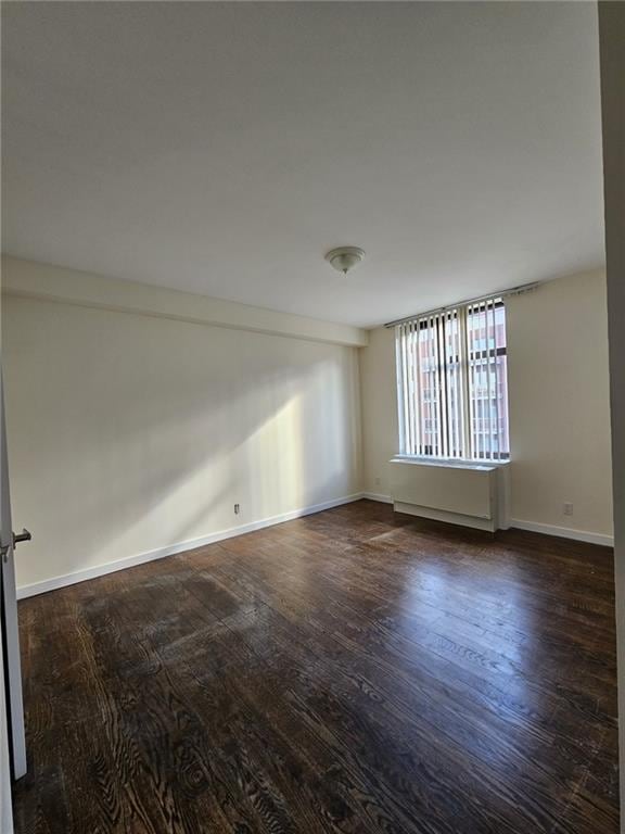 empty room featuring wood finished floors and baseboards