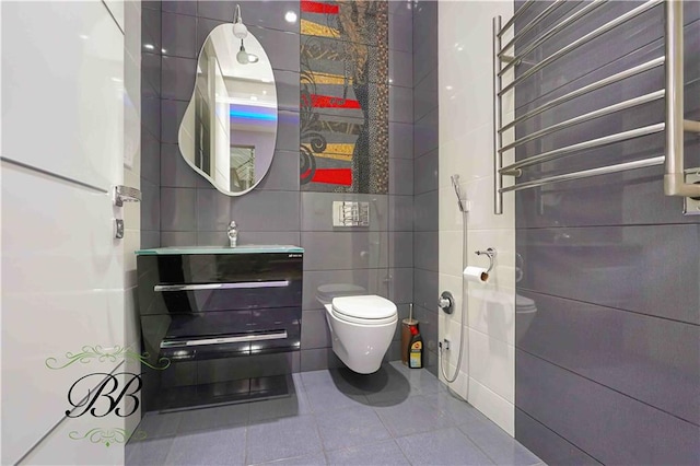 bathroom with toilet, tile patterned flooring, tile walls, and sink