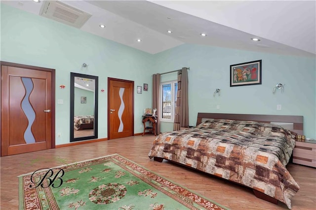 bedroom with light wood-type flooring and high vaulted ceiling