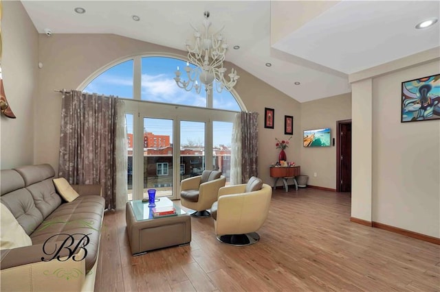 living room featuring a chandelier, vaulted ceiling, a wealth of natural light, and light hardwood / wood-style flooring