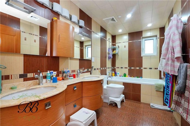 full bathroom with tile patterned floors, tile walls, toilet, vanity, and shower / bathtub combination