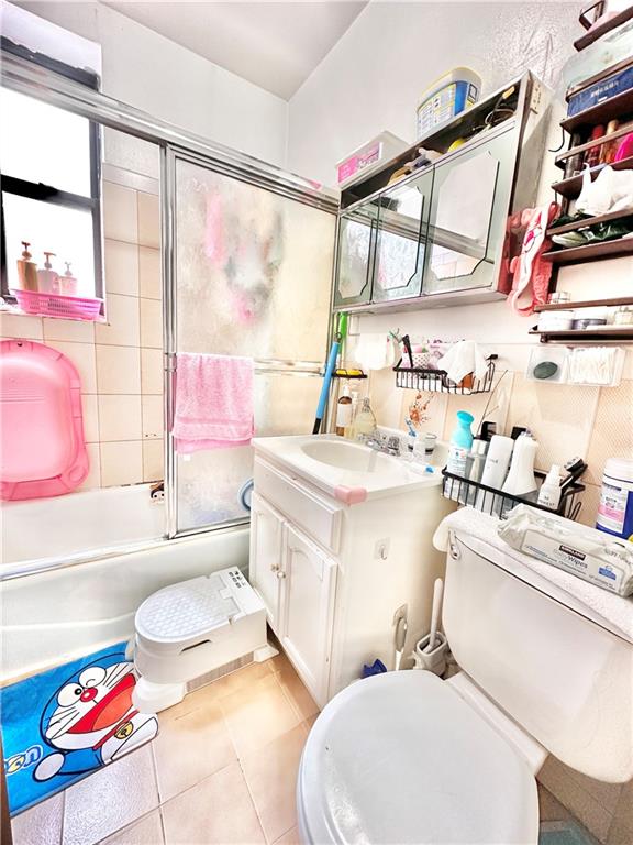 full bathroom with toilet, vanity, tile patterned floors, and enclosed tub / shower combo