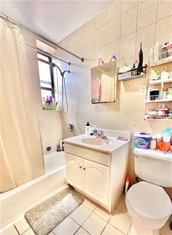 full bathroom featuring tile patterned floors, shower / bathtub combination with curtain, and tile walls