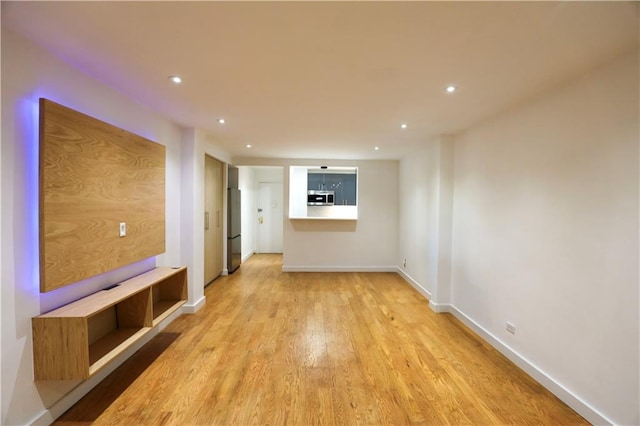 unfurnished living room featuring recessed lighting, baseboards, and light wood finished floors