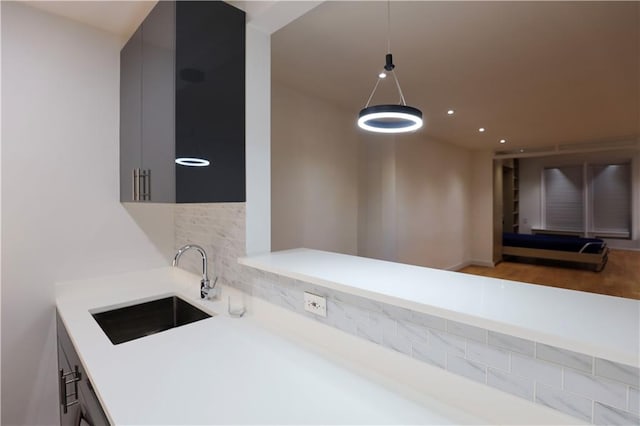 kitchen featuring a sink, backsplash, wood finished floors, and light countertops