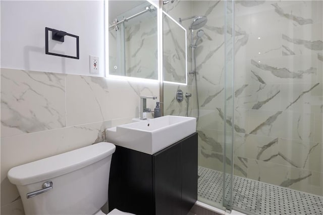 full bathroom with a marble finish shower, toilet, vanity, and tile walls