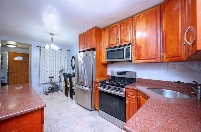 kitchen with sink, hanging light fixtures, stainless steel appliances, a notable chandelier, and decorative backsplash