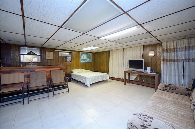 bedroom with a paneled ceiling and wood walls