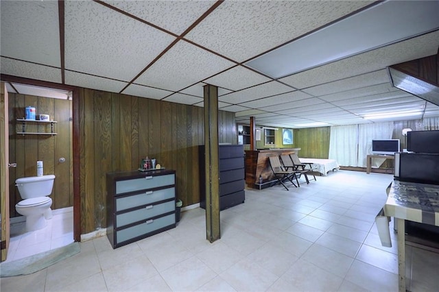 basement with a drop ceiling and wood walls