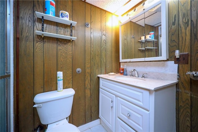 bathroom featuring vanity, wooden walls, and toilet