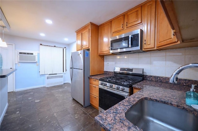 kitchen featuring pendant lighting, radiator, sink, appliances with stainless steel finishes, and a wall mounted air conditioner