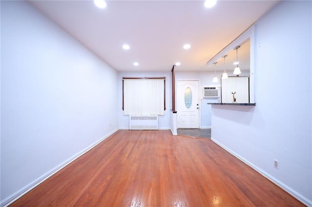 interior space featuring dark wood-type flooring, radiator heating unit, and a wall mounted air conditioner