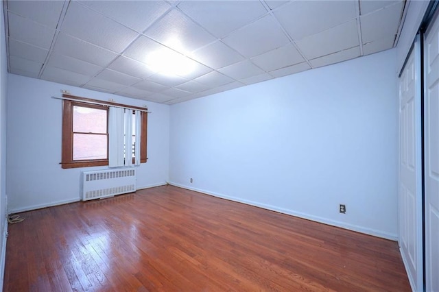 unfurnished room featuring a paneled ceiling, wood-type flooring, and radiator