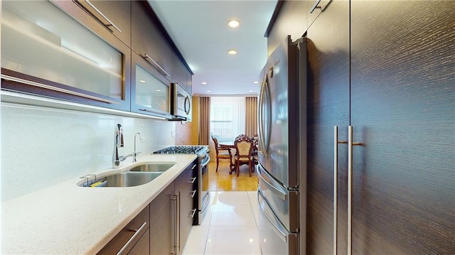 kitchen with light stone countertops, sink, light tile patterned floors, and appliances with stainless steel finishes