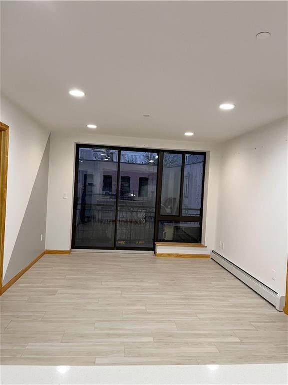 unfurnished room with a baseboard radiator and light hardwood / wood-style flooring