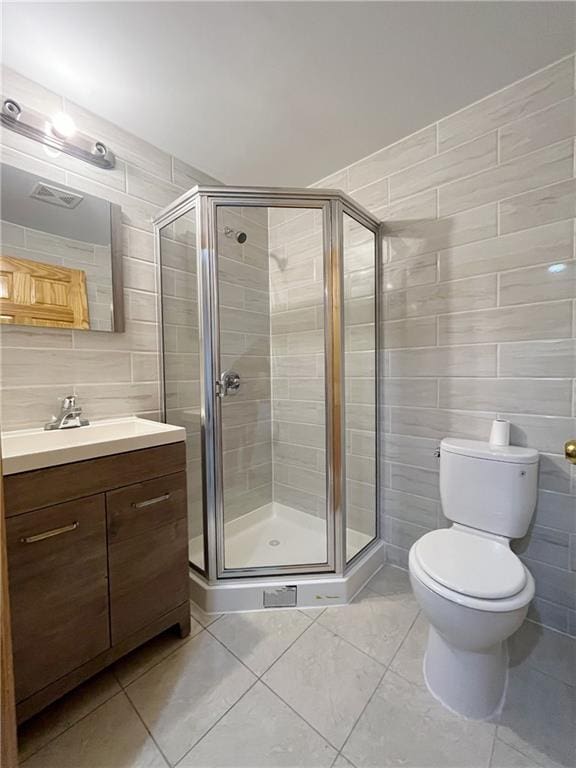 bathroom with walk in shower, toilet, tile walls, vanity, and tile patterned flooring