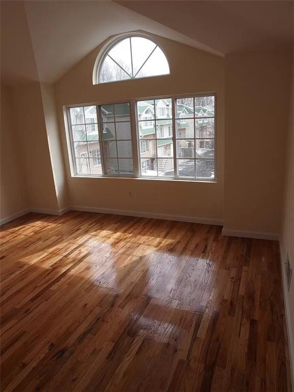 spare room with wood-type flooring and lofted ceiling