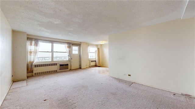 unfurnished room featuring radiator heating unit, a textured ceiling, and light carpet