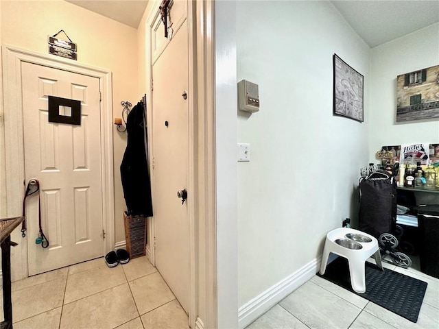 hallway with light tile patterned flooring and baseboards