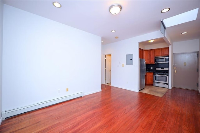 kitchen featuring backsplash, dark wood-type flooring, a skylight, baseboard heating, and appliances with stainless steel finishes