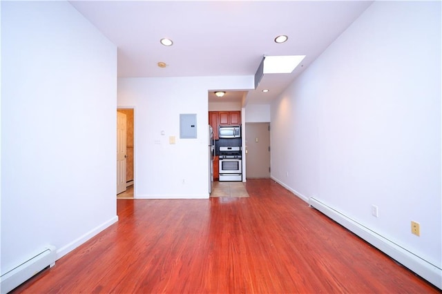 spare room with a skylight, wood-type flooring, electric panel, and a baseboard heating unit