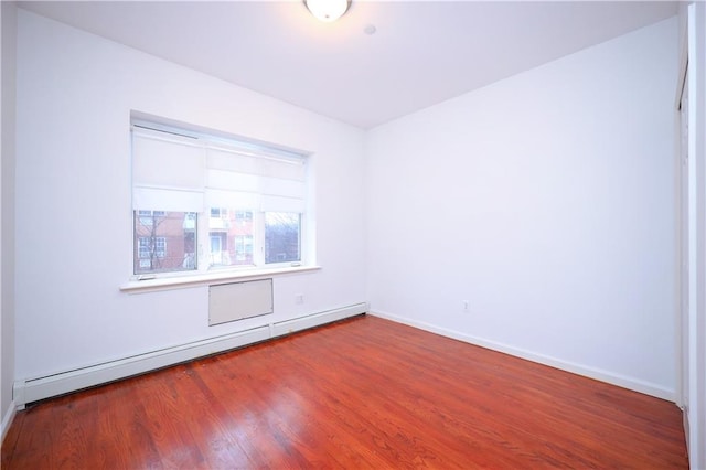 empty room with wood-type flooring and baseboard heating