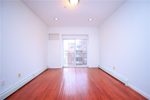 empty room featuring wood-type flooring and a baseboard radiator