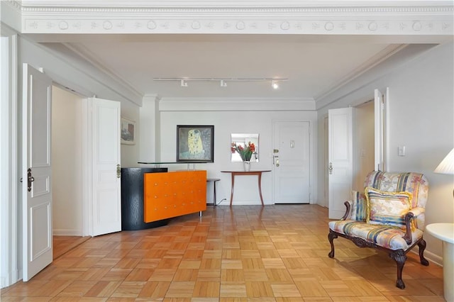 interior space featuring rail lighting, baseboards, and ornamental molding