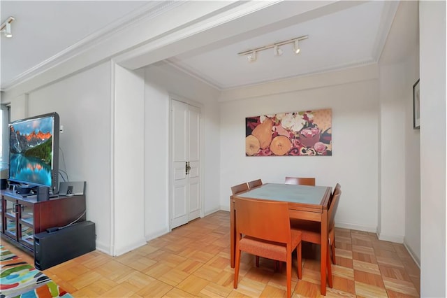 dining space featuring rail lighting, baseboards, and ornamental molding