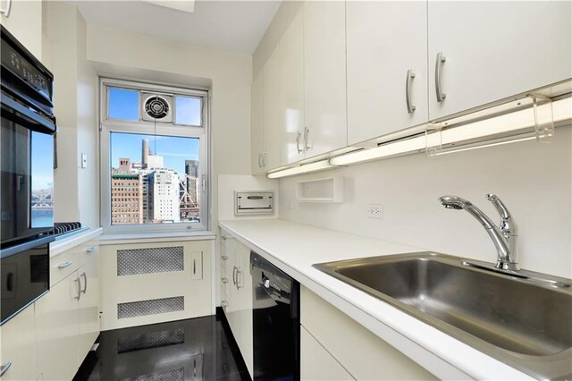 kitchen featuring black appliances, a sink, light countertops, and white cabinets