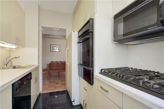 kitchen with a warming drawer, black appliances, a sink, and light countertops