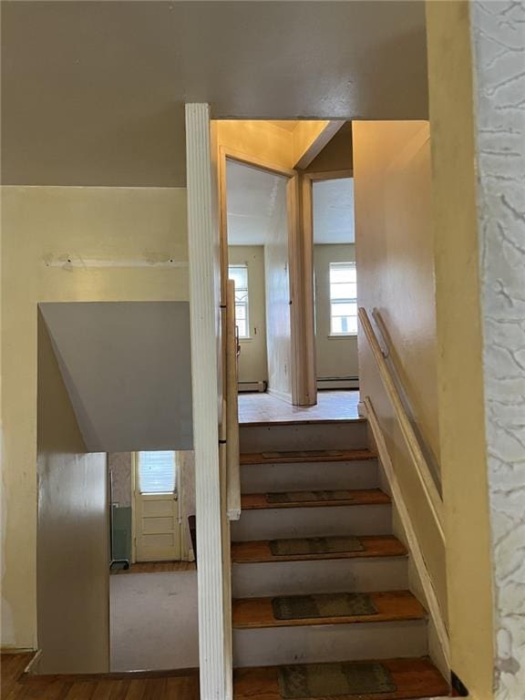 stairs featuring baseboard heating and hardwood / wood-style flooring