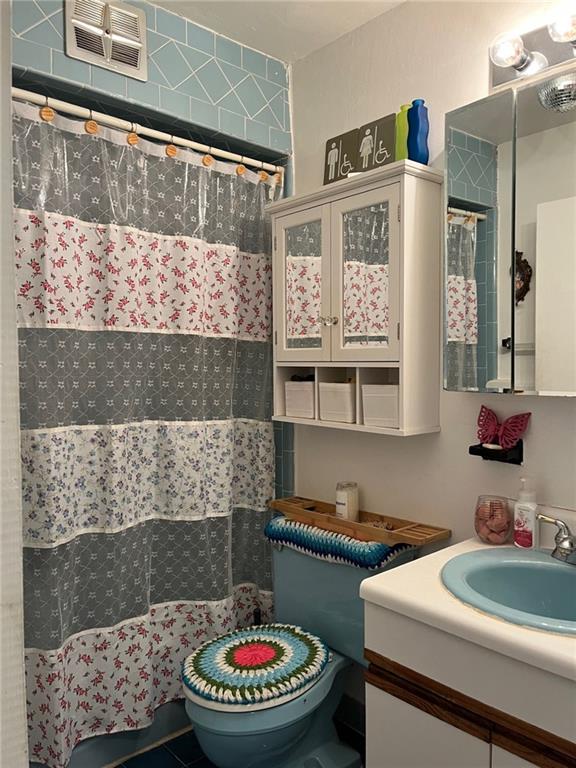 bathroom with toilet, walk in shower, and vanity