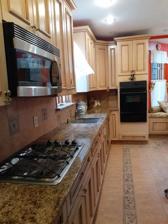 kitchen featuring sink, light stone countertops, appliances with stainless steel finishes, light tile patterned floors, and light brown cabinetry