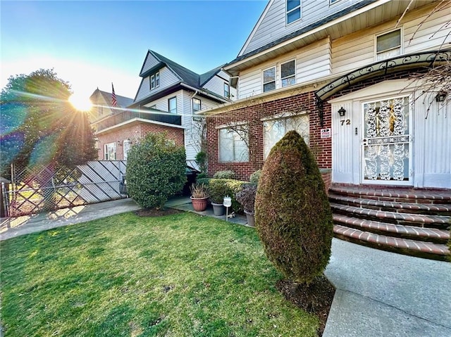 view of front of house featuring fence, a front lawn, and brick siding